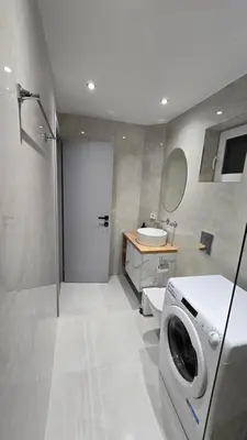 a bathroom with a shower and a sink and a washing machine at S&A apartments in Piraeus