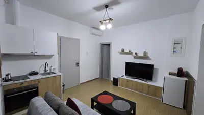 a white living room with a couch and a kitchen at S&A apartments in Piraeus