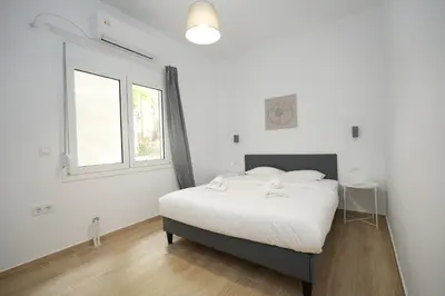 a white bedroom with a bed and a window at Central 1 BDRM apartment, in Pangrati in Athens