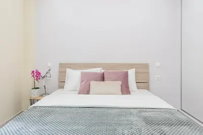 a white bedroom with a bed with pink and white pillows at Home near Flisvos Marina in Athens