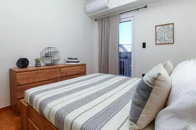 a bedroom with a bed and a dresser and a window at Defner Tzo's Modern Apartment in Athens