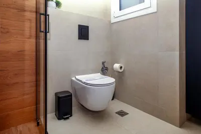 a bathroom with a white toilet and a window at Defner Tzo's Modern Apartment in Athens