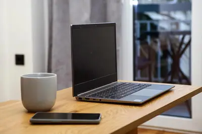 a laptop computer sitting on a table next to a cup at Defner Tzo's Modern Apartment in Athens