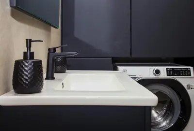 a sink in a bathroom next to a washing machine at Defner Tzo's Modern Apartment in Athens