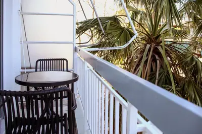 a table and chair on a balcony with a palm tree at Defner Tzo's Modern Apartment in Athens