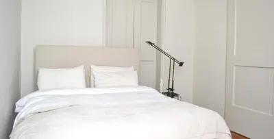 a bedroom with a bed with white sheets and a lamp at Central Athenian Maison, with Acropolis Views in Athens