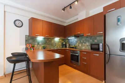 a kitchen with wooden cabinets and a refrigerator at Cozy Athenian Hideaway in the heart of Pangrati in Athens