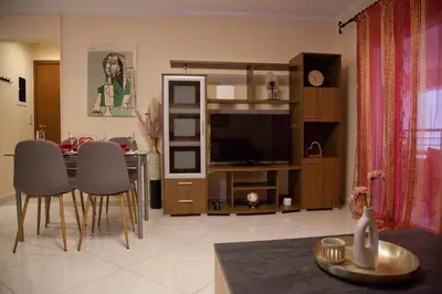 a living room with a television and a table with chairs at Lovely Nest Piraeus Premium in Piraeus
