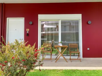 a red house with a table and chairs on a patio at Mocha Luxury Residence in Spáta
