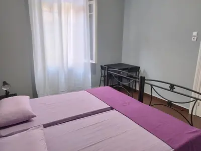 a bedroom with two beds with purple sheets and a window at Remoundou 18 rental room in Athens