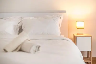 a white bed with white pillows and a lamp at Athens F&K Premium City Home in Athens