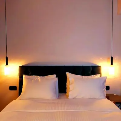 a bedroom with a bed with white pillows and lights at The Dream Suite in Piraeus