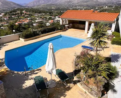 a swimming pool with chairs and an umbrella on a house at Bella Vista pool Villas in Anavissos in Barbaliáki