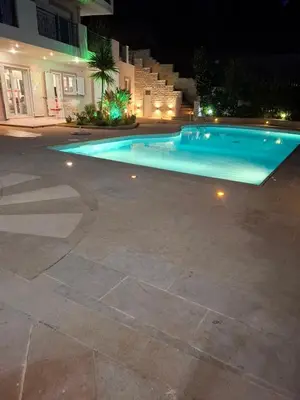 a large swimming pool at night with a building at Bella Vista pool Villas in Anavissos in Barbaliáki