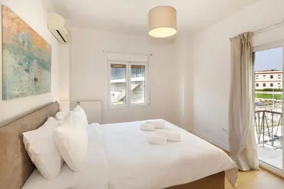 a white bedroom with a large bed and a window at Acropolis Museum Retreat by GHH in Athens