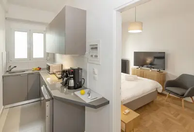 a room with a kitchen and a bedroom with a bed at Acropolis Museum Retreat by GHH in Athens