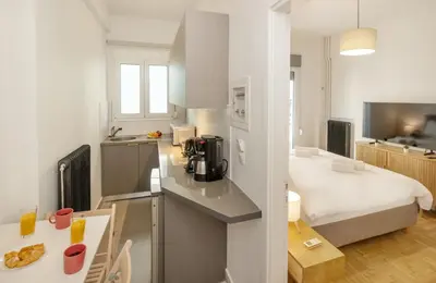 a kitchen with a counter top and a room with a bed at Acropolis Museum Retreat by GHH in Athens