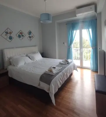 a bedroom with a large bed with blue curtains at Alexandras Park View in Athens