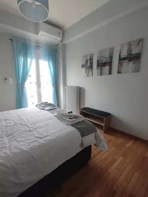 a bedroom with a bed with blue curtains and a window at Alexandras Park View in Athens