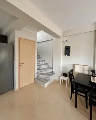 a living room with a table and a staircase at Pearl Villa and Apartment near Beach and Athens Airport in Porto Rafti