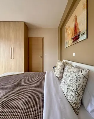 a bedroom with a bed and a painting on the wall at Pearl Villa and Apartment near Beach and Athens Airport in Porto Rafti