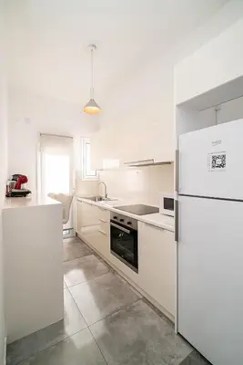 a white kitchen with a refrigerator and a sink at Athens Due Montagne Apartment in Athens