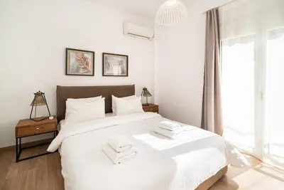 a white bedroom with a large bed with two towels on it at Athens Due Montagne Apartment in Athens