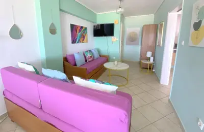 a living room with a pink couch and a table at MediTerra Stay Anavyssos Seaview in Áyios Yeóryios