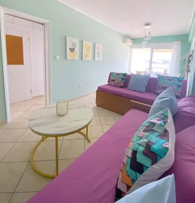 a living room with a purple couch and a table at MediTerra Stay Anavyssos Seaview in Áyios Yeóryios