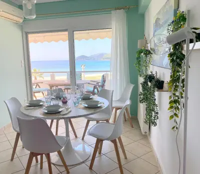 a dining room with a table and chairs and a view of the ocean at MediTerra Stay Anavyssos Seaview in Áyios Yeóryios