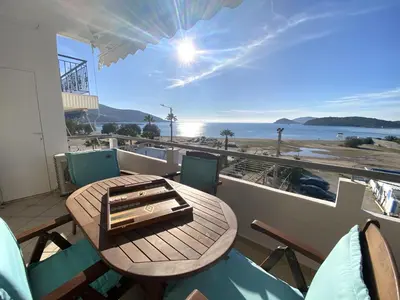 a table and chairs on a balcony with a view of the beach at MediTerra Stay Anavyssos Seaview in Áyios Yeóryios