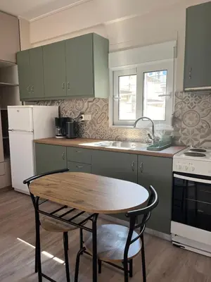 a kitchen with green cabinets and a wooden table at Nina's Home in Athens