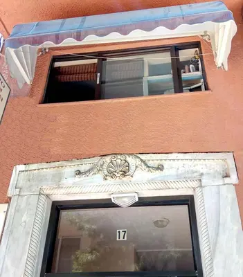 a window on a building with an avertisement at OneStep in Athens by Oinapothiki Taverna! in Athens