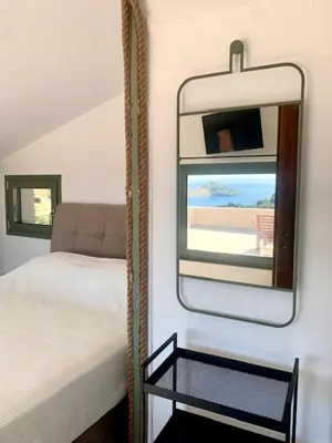 a bedroom with a mirror next to a bed at Ersi's View in Porto Rafti