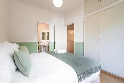 a bedroom with a white bed and green and white walls at STELLIE Elegant Mid-century modern 2bd-2bath in Athens