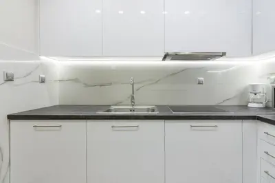 a white kitchen with a sink and white cabinets at Centrally Located Apt for 3 People in Athens
