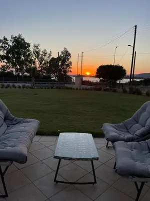 a patio with two couches and a table and the sunset at Serene Seaside Villa Raf with Unique Sunset View in Nisídhes Markéllou