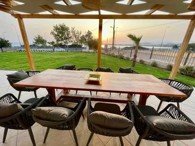 a wooden table and chairs under an umbrella at Serene Seaside Villa Raf with Unique Sunset View in Nisídhes Markéllou