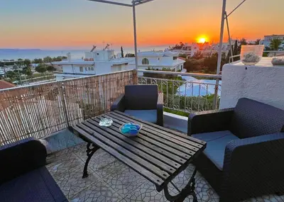 a table and chairs on a balcony with a sunset at Exclusive Penthouse Apt, at Glyfada Marina & Beach in Athens
