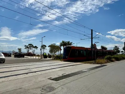 a red train is on the tracks on a street at Exclusive Penthouse Apt, at Glyfada Marina & Beach in Athens