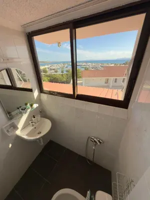 a bathroom with a window and a toilet and a sink at Exclusive Penthouse Apt, at Glyfada Marina & Beach in Athens