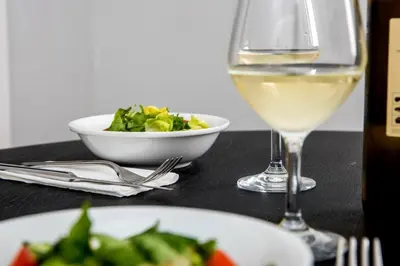 a table with a glass of wine and a bowl of salad at The Athenian Veranda in Athens