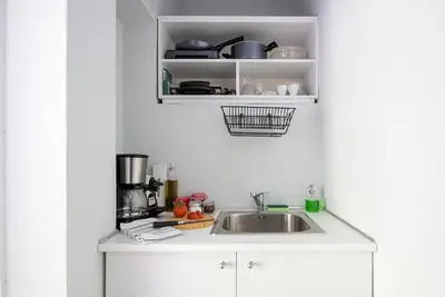 a kitchen with a sink and a shelf with pots and pans at The Athenian Veranda 2 in Athens