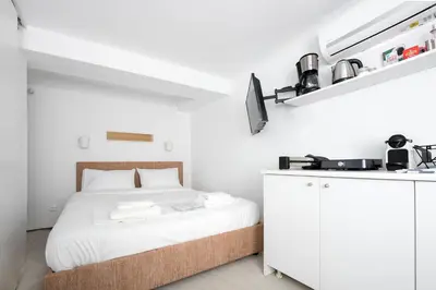 a white bedroom with a bed and a tv at The Athenian Veranda 3 in Athens