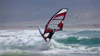 a person on a surfboard with a sail on the ocean at Artistic & cozy ! Just 5' to seaside in Athens