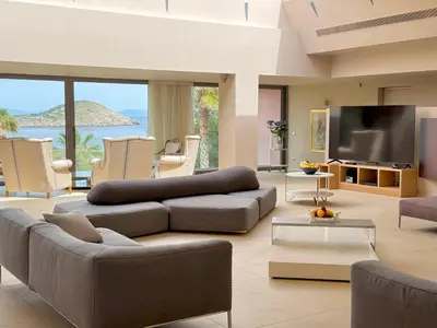 a living room with a couch and a television at Blue Angel Villa Luxury Seafront Estate in Porto Rafti