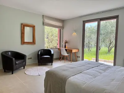 a bedroom with a bed and a desk and chairs at Blue Angel Villa Luxury Seafront Estate in Porto Rafti