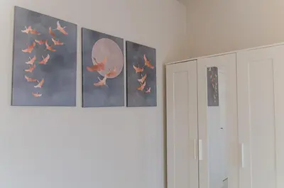 a row of paintings on a wall next to a white cabinet at Green apartment in Piraeus