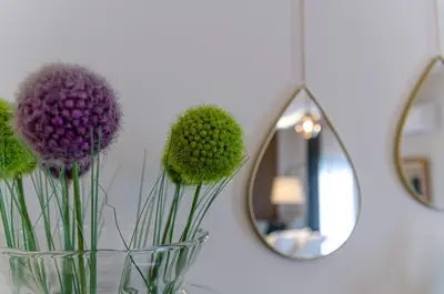 a vase with purple flowers in front of a mirror at Green apartment in Piraeus