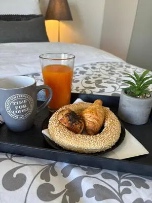 a tray with a plate of food and a cup of orange juice at Kallitheas Maison with Shared Pool in Athens